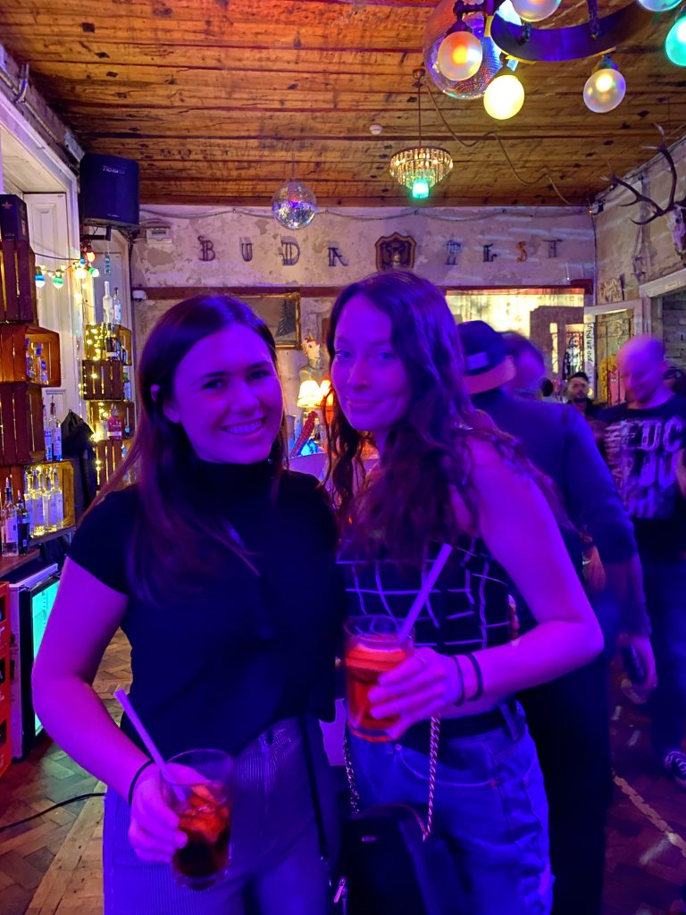 Two women holding drinks together in a bar in Budapest, Hungary.