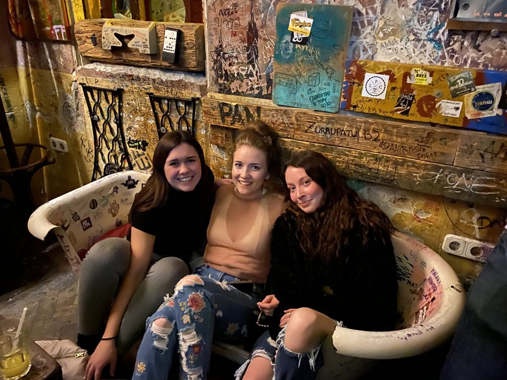 3 women sitting inside of a bathtub in a bar in Budapest.